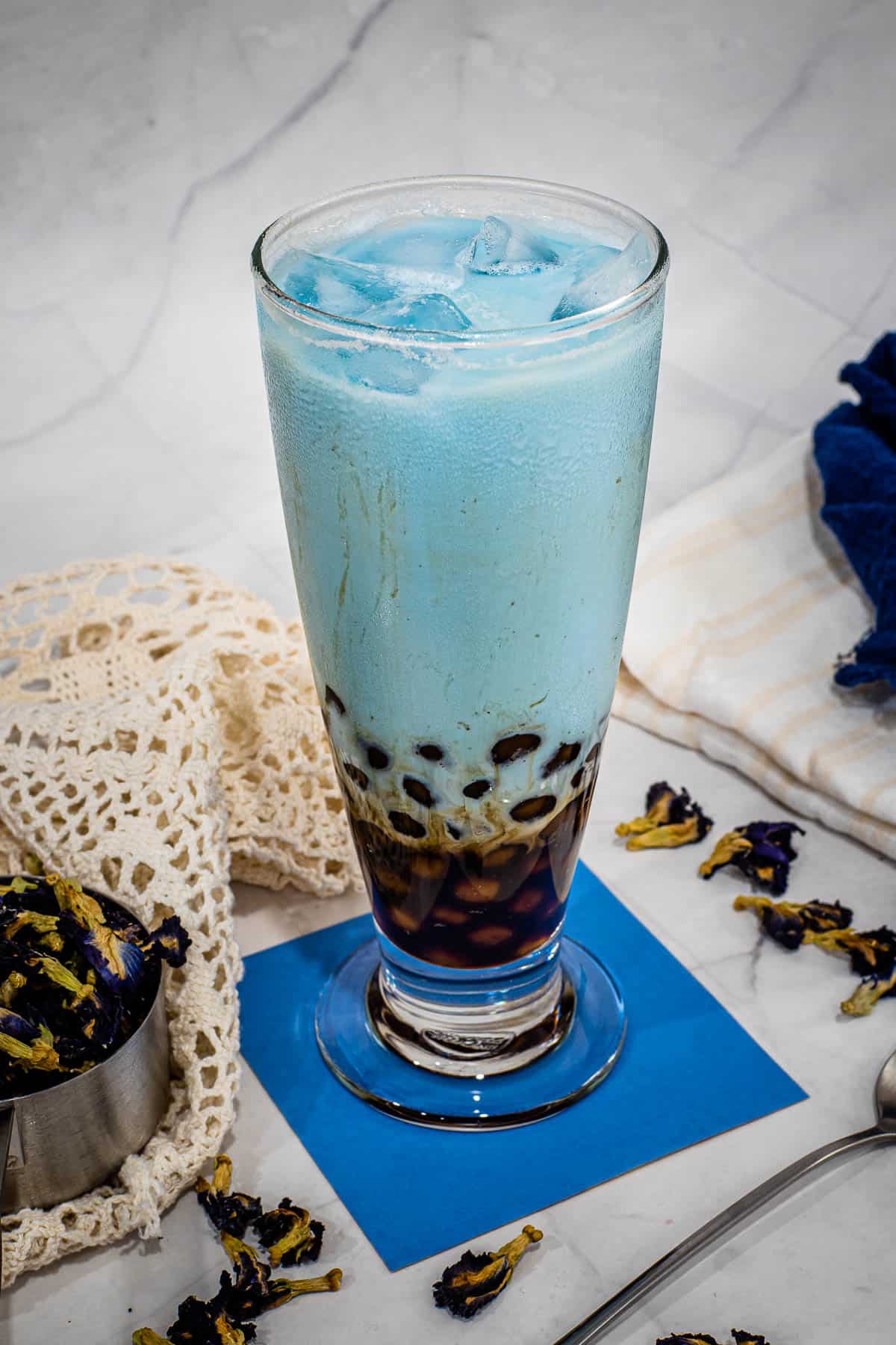 A glass of iced butterfly pea flower milk tea with boba pearls.
