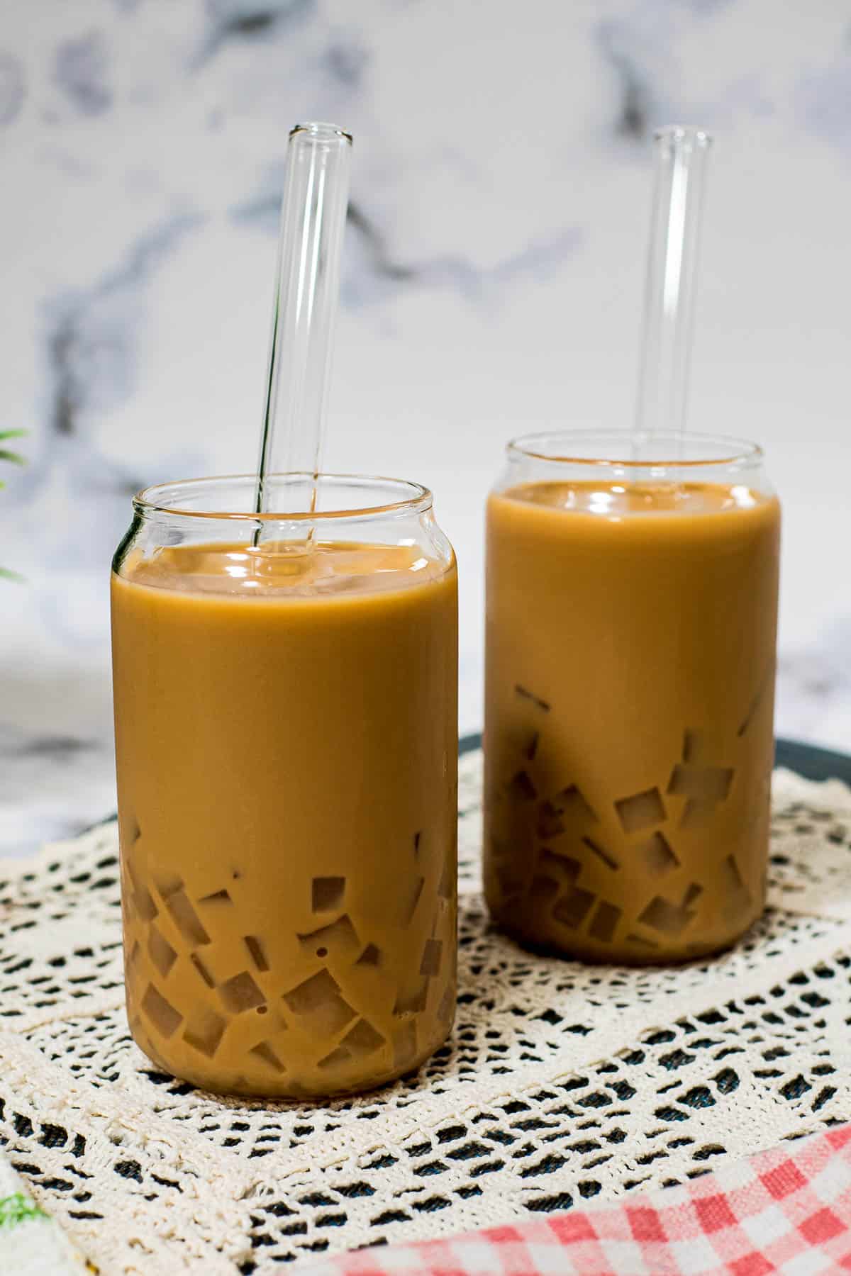 Two glasses of iced tea with bubble tea straws.
