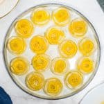 Round mango konnyaku jelly dessert on a grey plate.