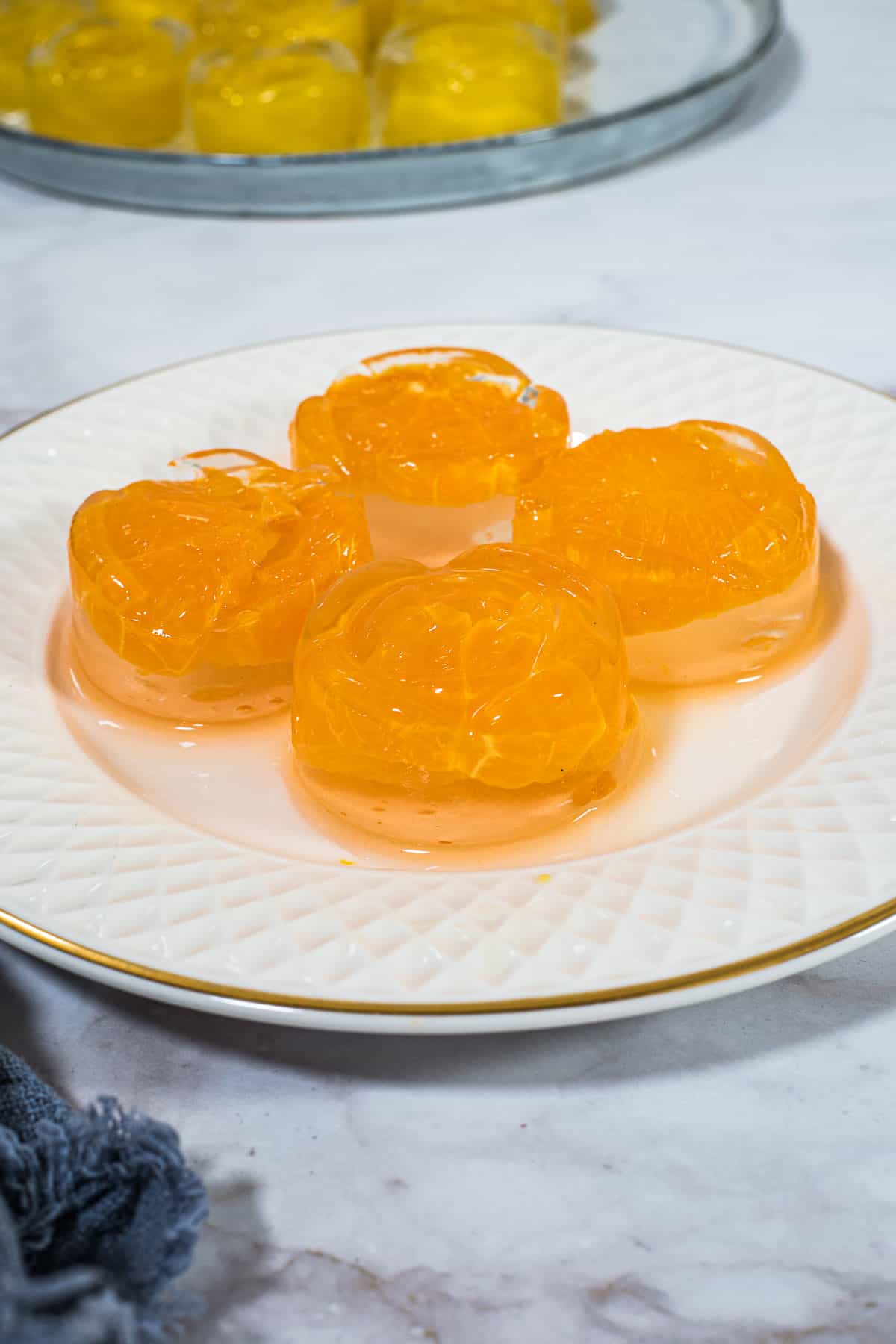 4 round orange jellies on a white plate.