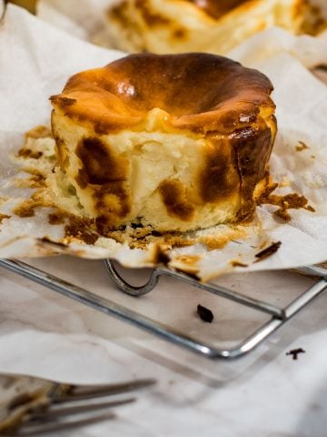 A mini burnt cheesecake with its parchment lining peeled off.