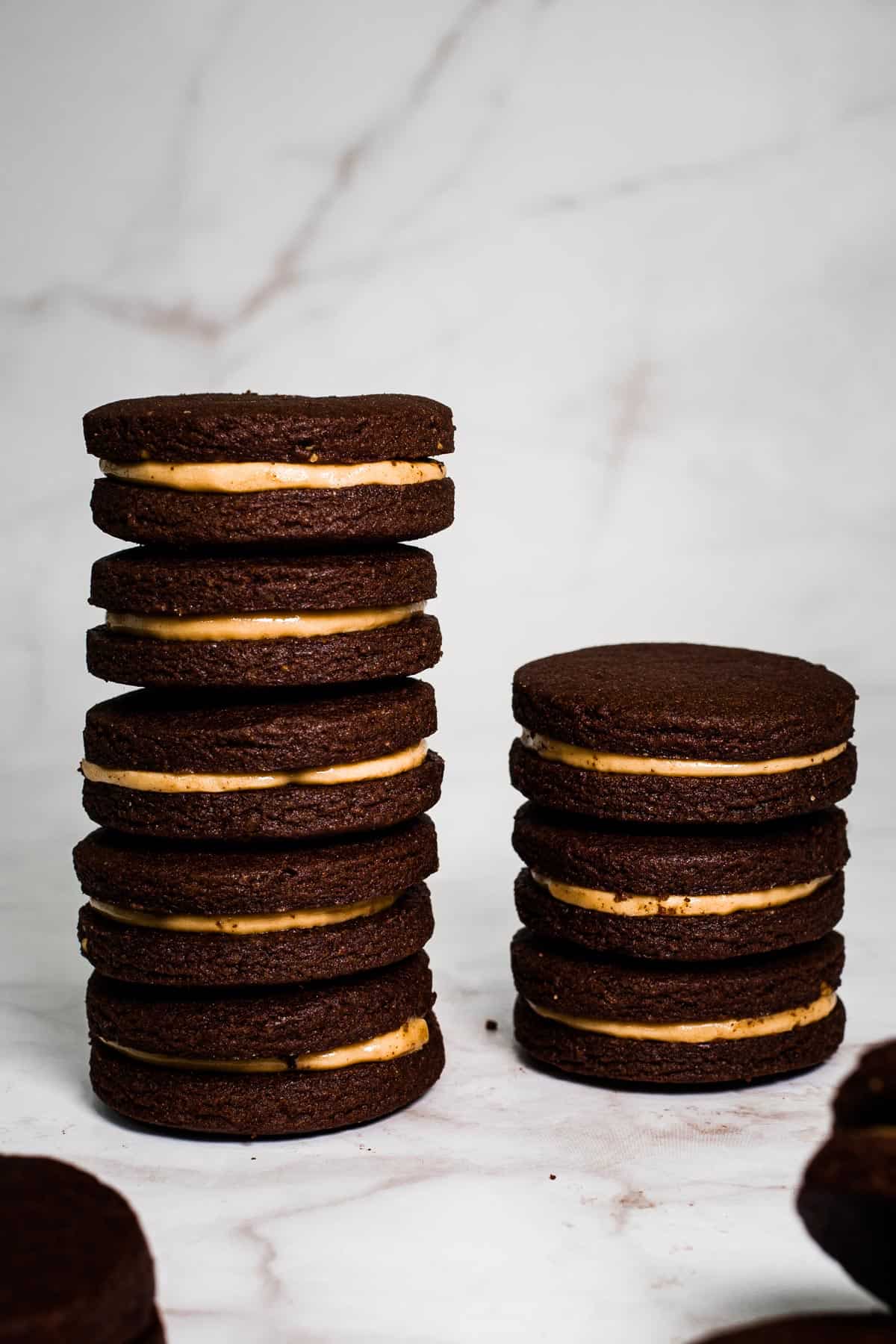 Two stacks of chocolate peanut butter sandwich cookies.