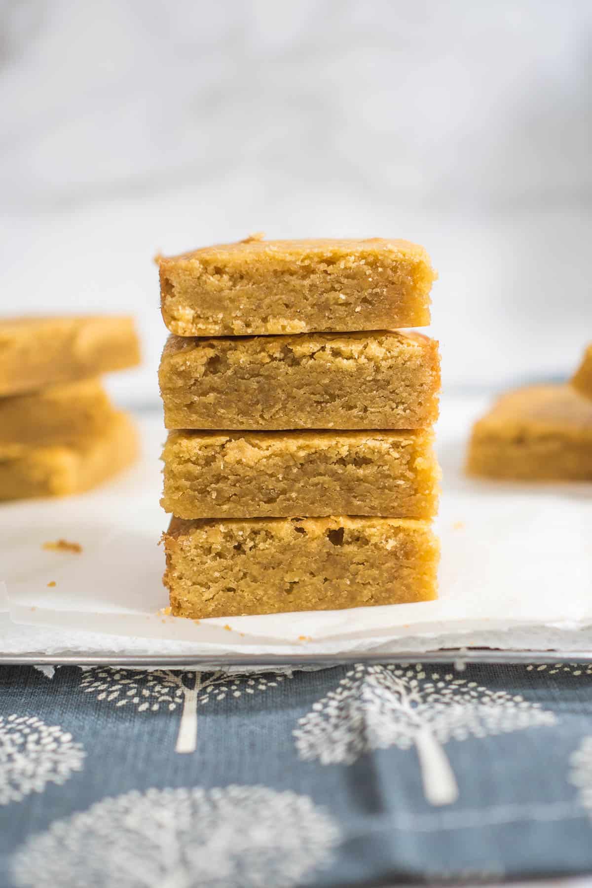 A stack of 4 bars of blondies on a parchment paper.