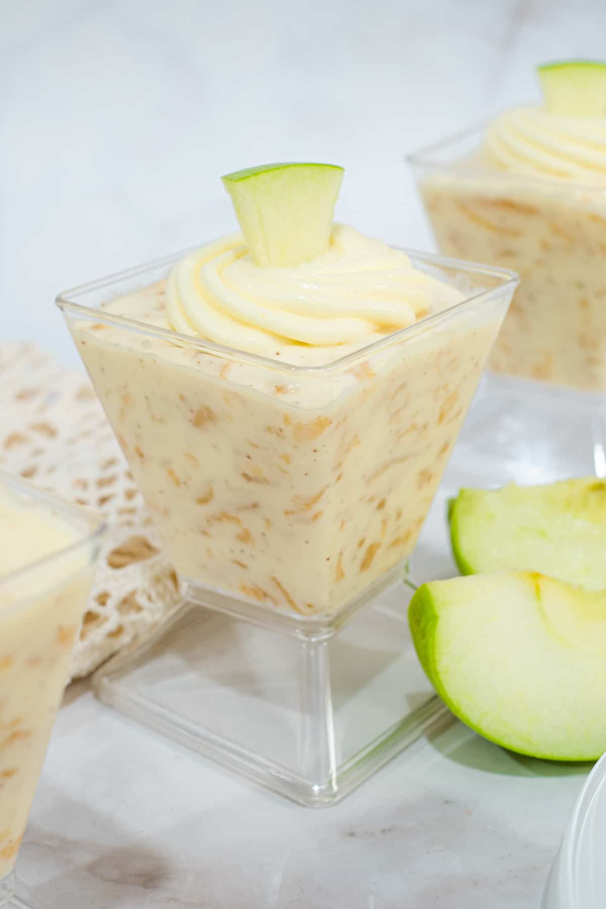 Apple mousse in a cup garnished with a slice of apple.