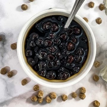 Top view of a bowl filled with boba pearls in dark syrup.