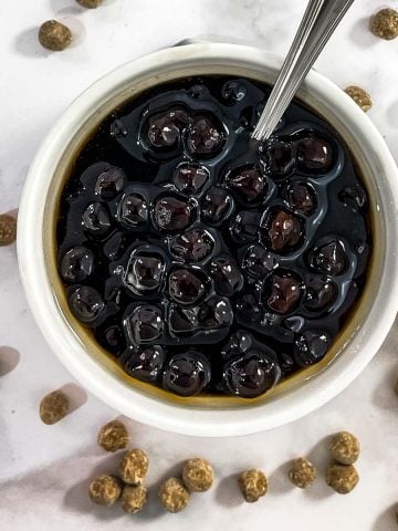Top view of a bowl filled with boba pearls in dark syrup.