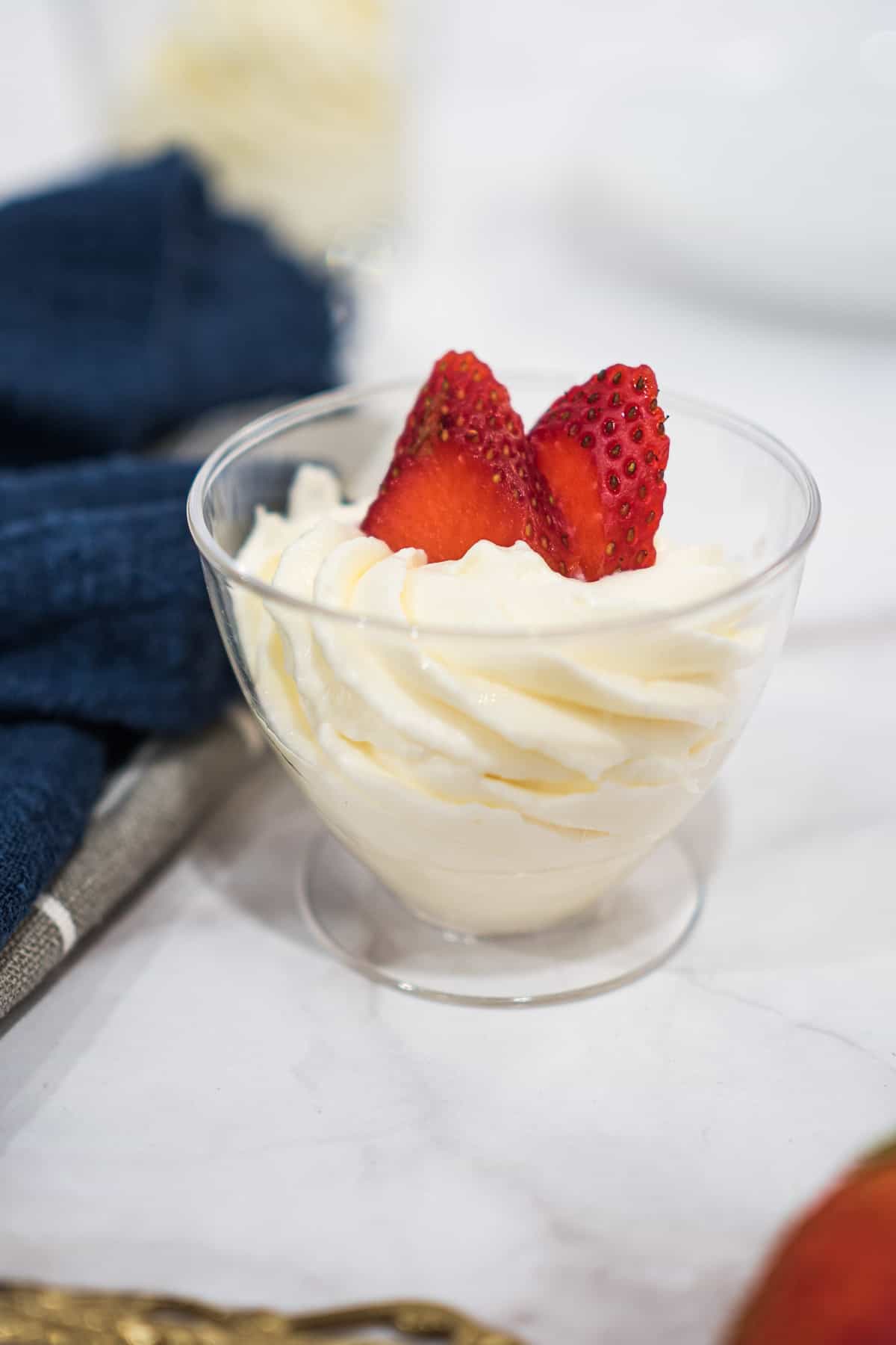 Mascarpone whipped cream frosting piped into a glass and decorated with strawberry slices.