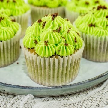 A few green cupcakes on a grey plate.