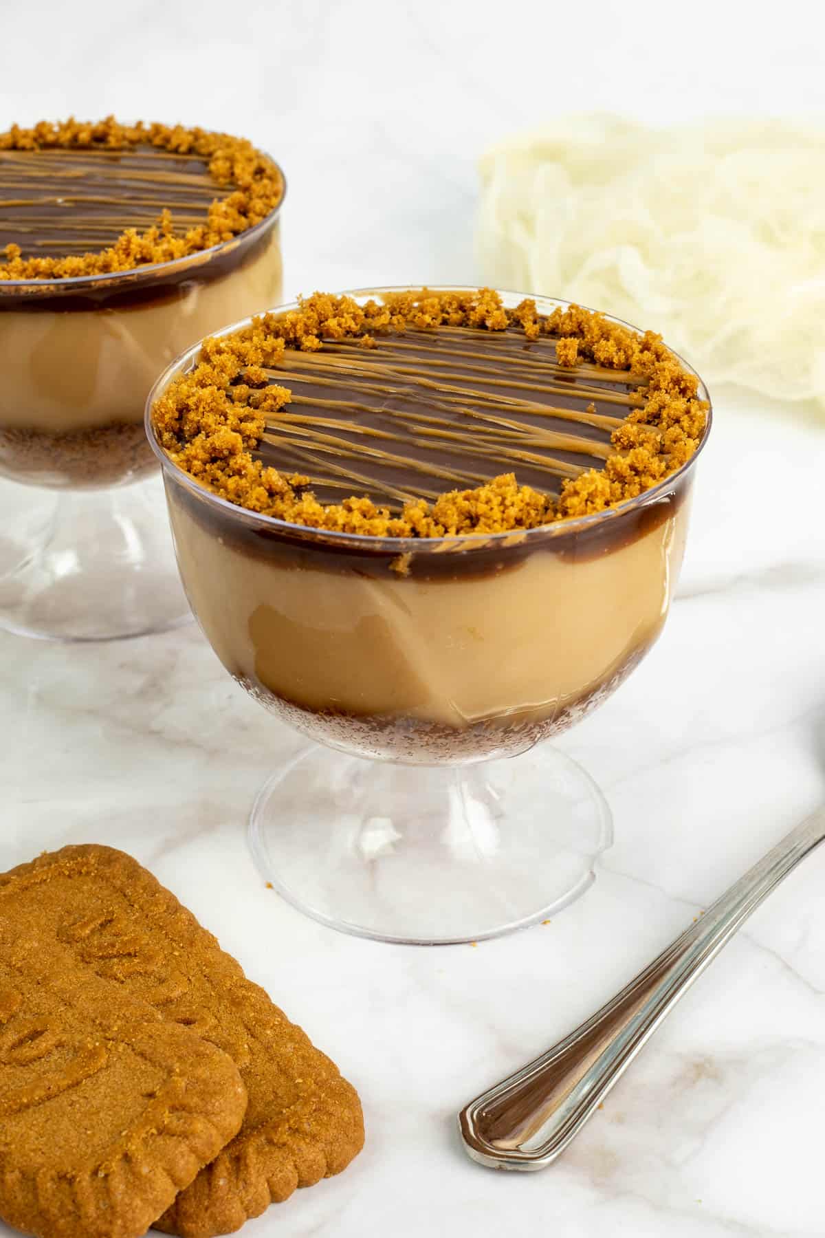A cup of brown pudding with chocolate and biscoff topping.