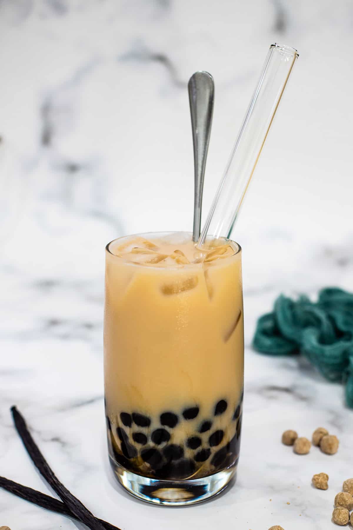A glass of vanilla milk tea with brown sugar pearls.