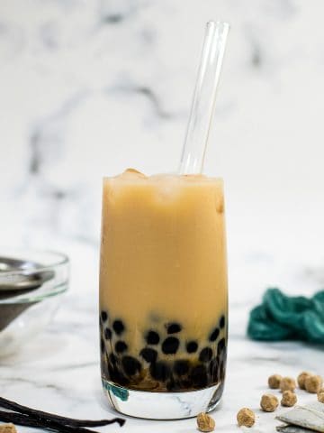 A glass of vanilla milk tea with brown sugar pearls.