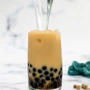 A glass of vanilla boba tea with brown sugar pearls.