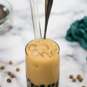 A glass of vanilla boba tea with brown sugar pearls.
