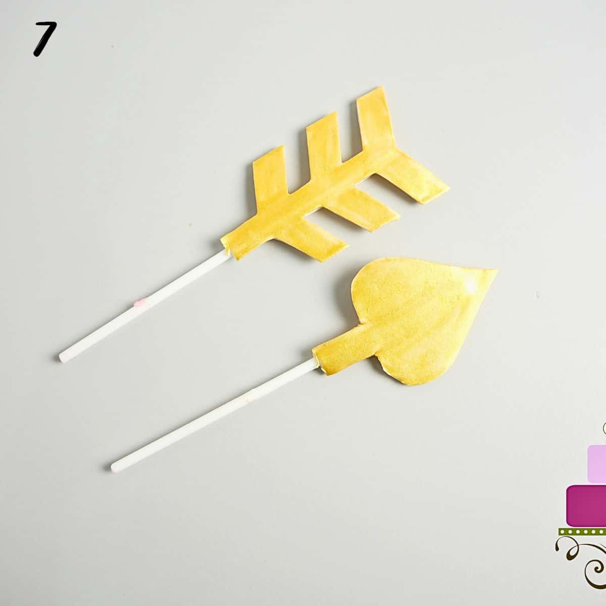 Gold arrows with lollipop sticks attached.