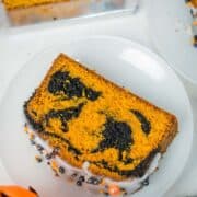 A slice of orange and black cake on a white plate.