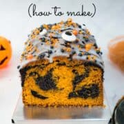 An orange and black marble loaf cake with white glaze and orange and black and eyeball candy sprinkles.