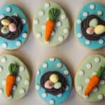 Egg shaped cookies with green and blue background and carrots and eggs toppers.