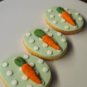 3 egg shaped cookies with carrot toppers.