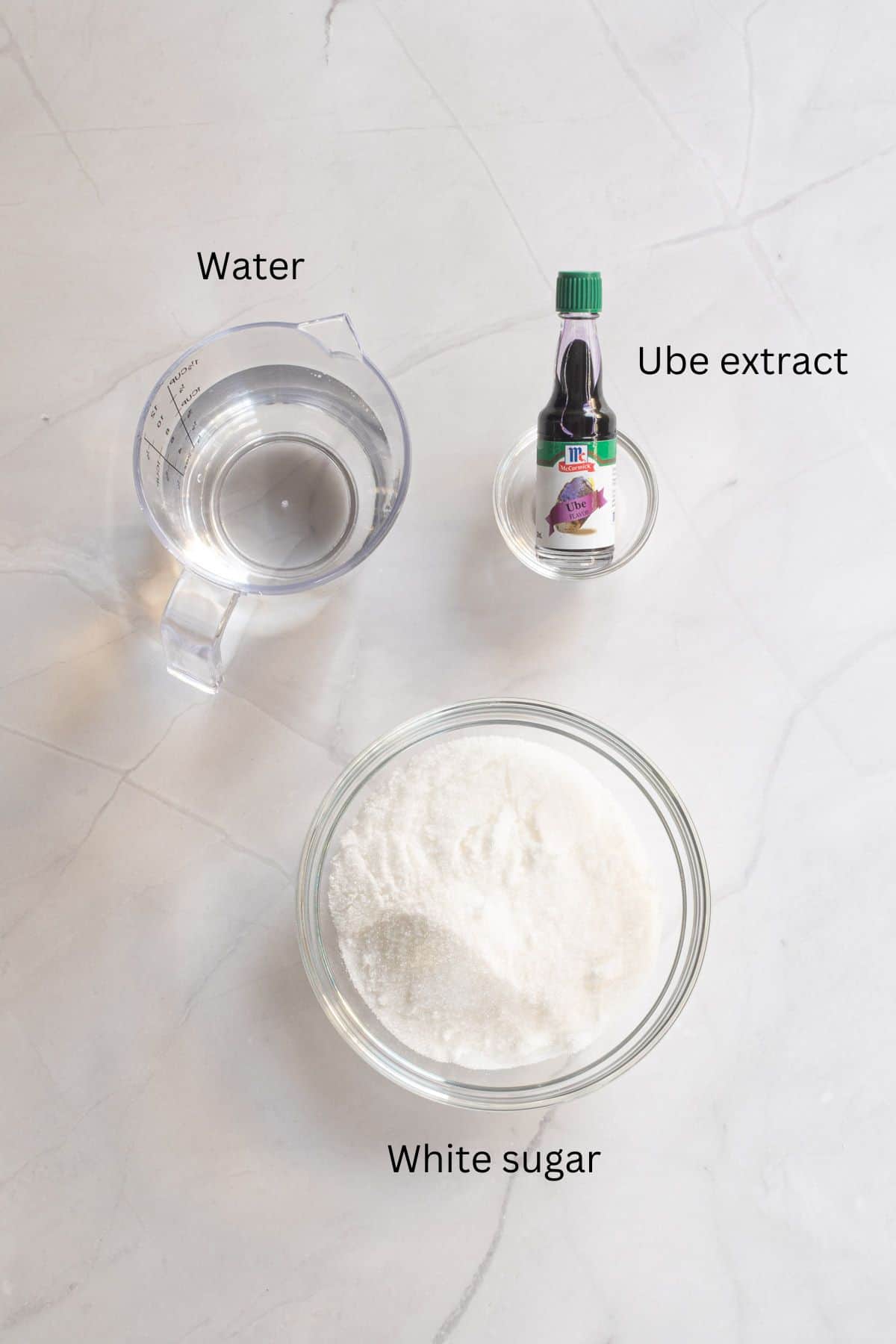 Water, sugar and ube extract against a marble background.