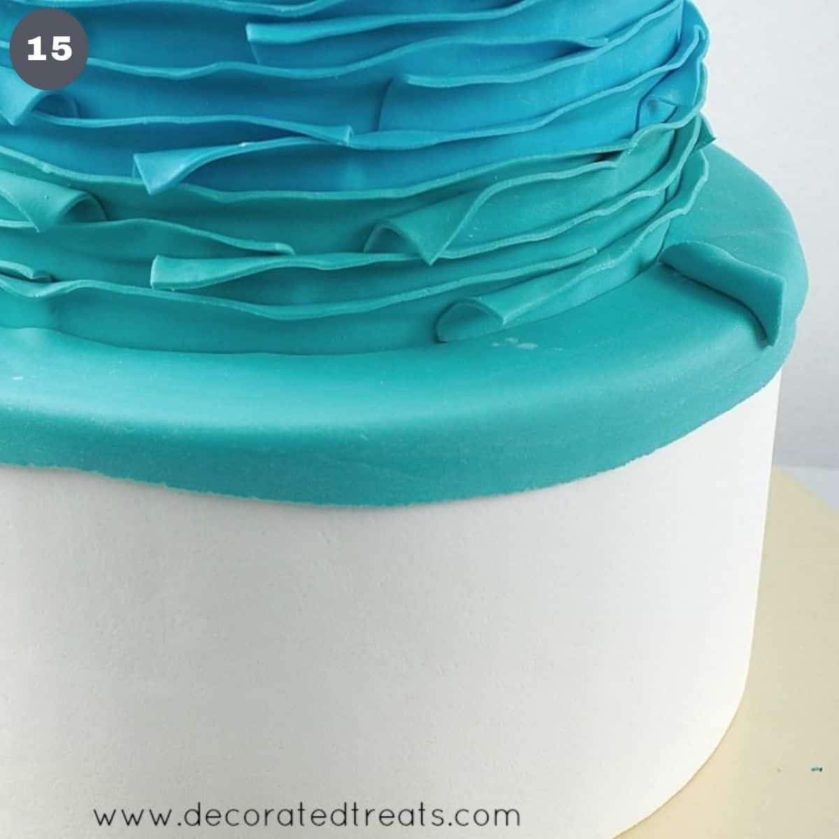 A cake covered in stripes of fondant in blue, turquoise and green.