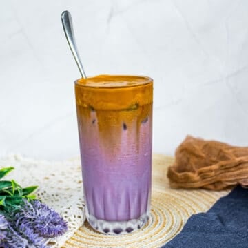 A glass of purple milk topped with whipped coffee.