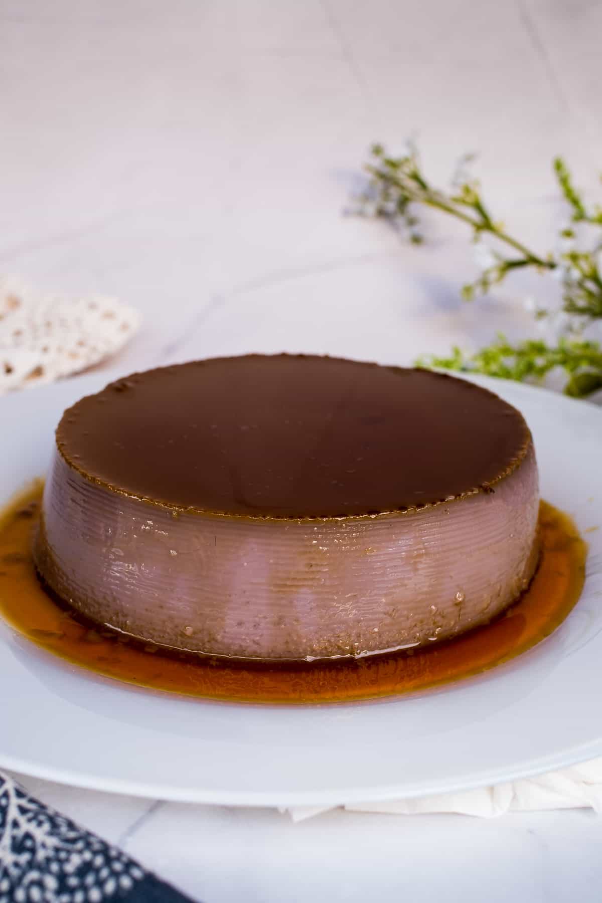 Round ube leche flan on a white plate.