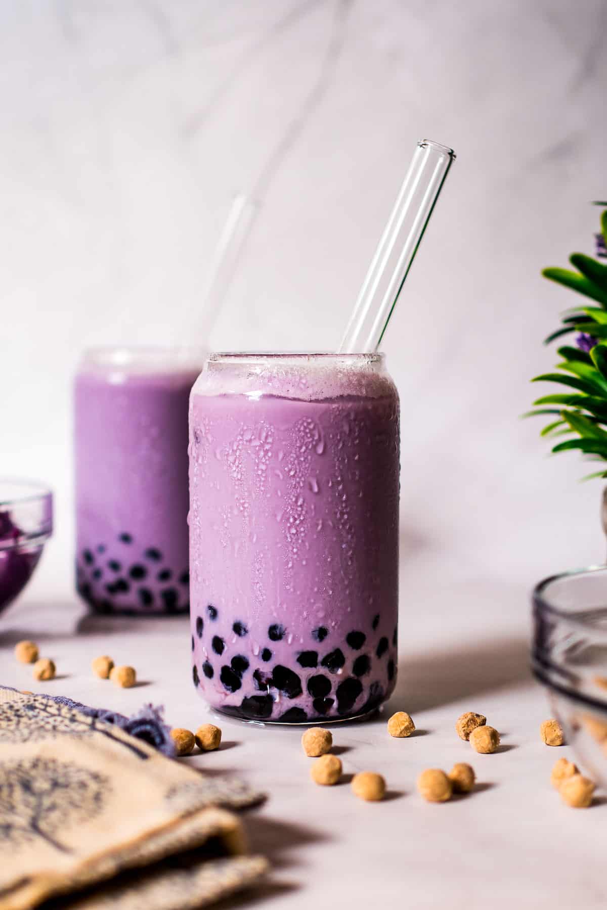 Two glasses of purple drink with boba pearls.