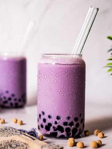 Two glasses of purple drink with boba pearls.