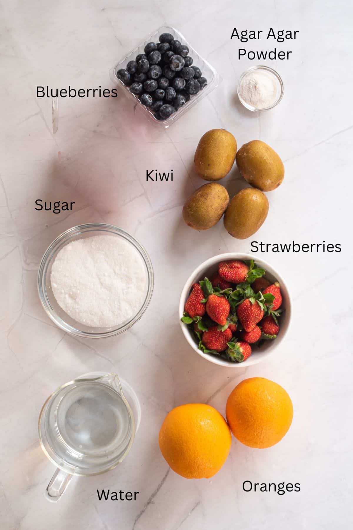 Blueberries, strawberries, kiwis, oranges, agar agar powder, sugar and water against a marble background.