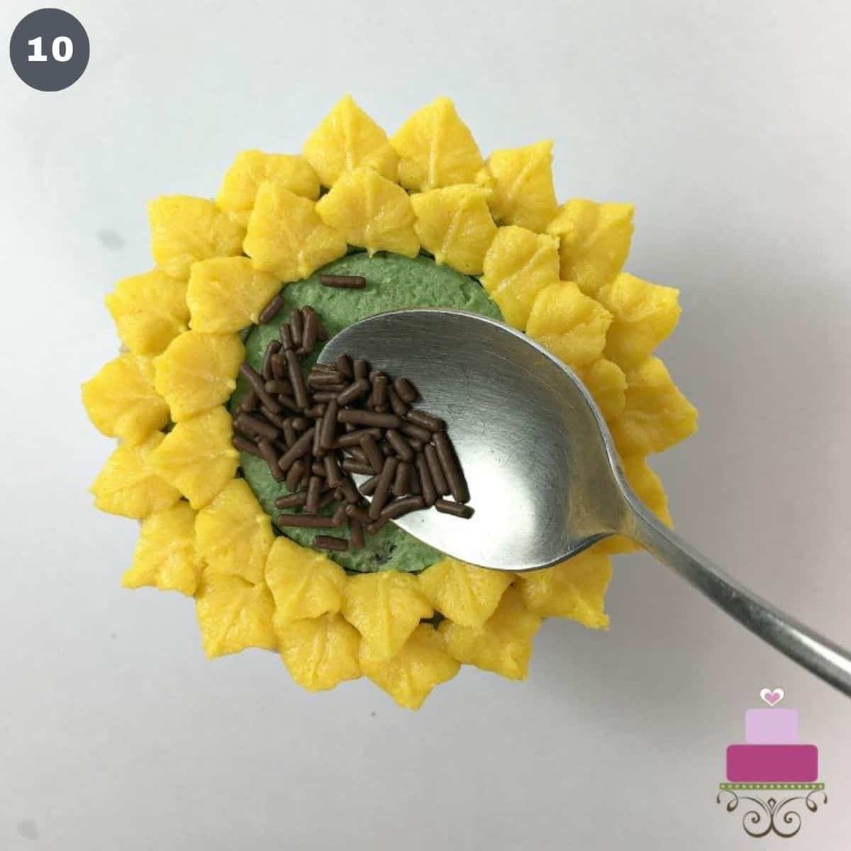 Adding chocolate sprinkles to the center of a sunflower cupcake.