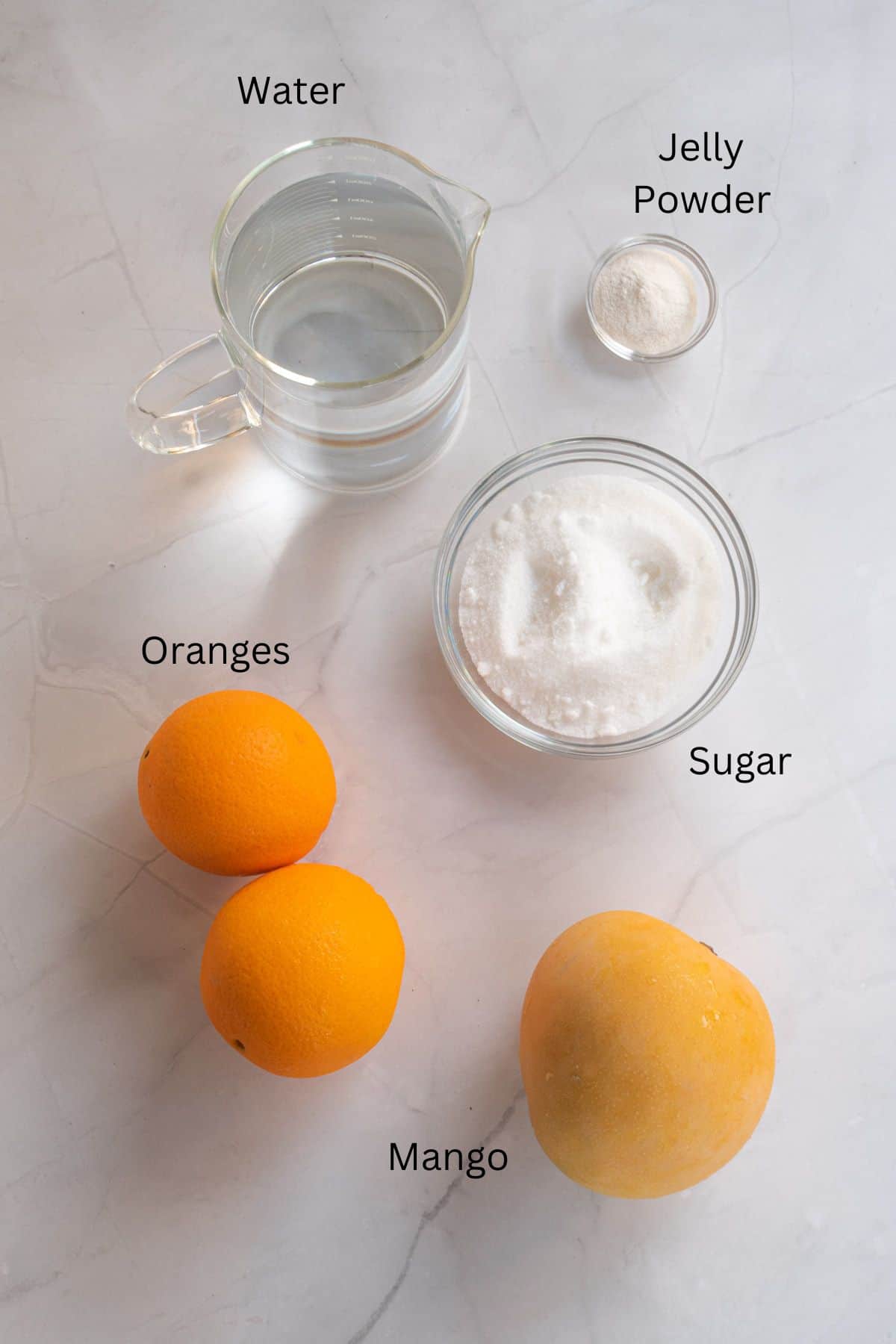 Water, jelly powder, sugar, oranges and mango against a marble background.