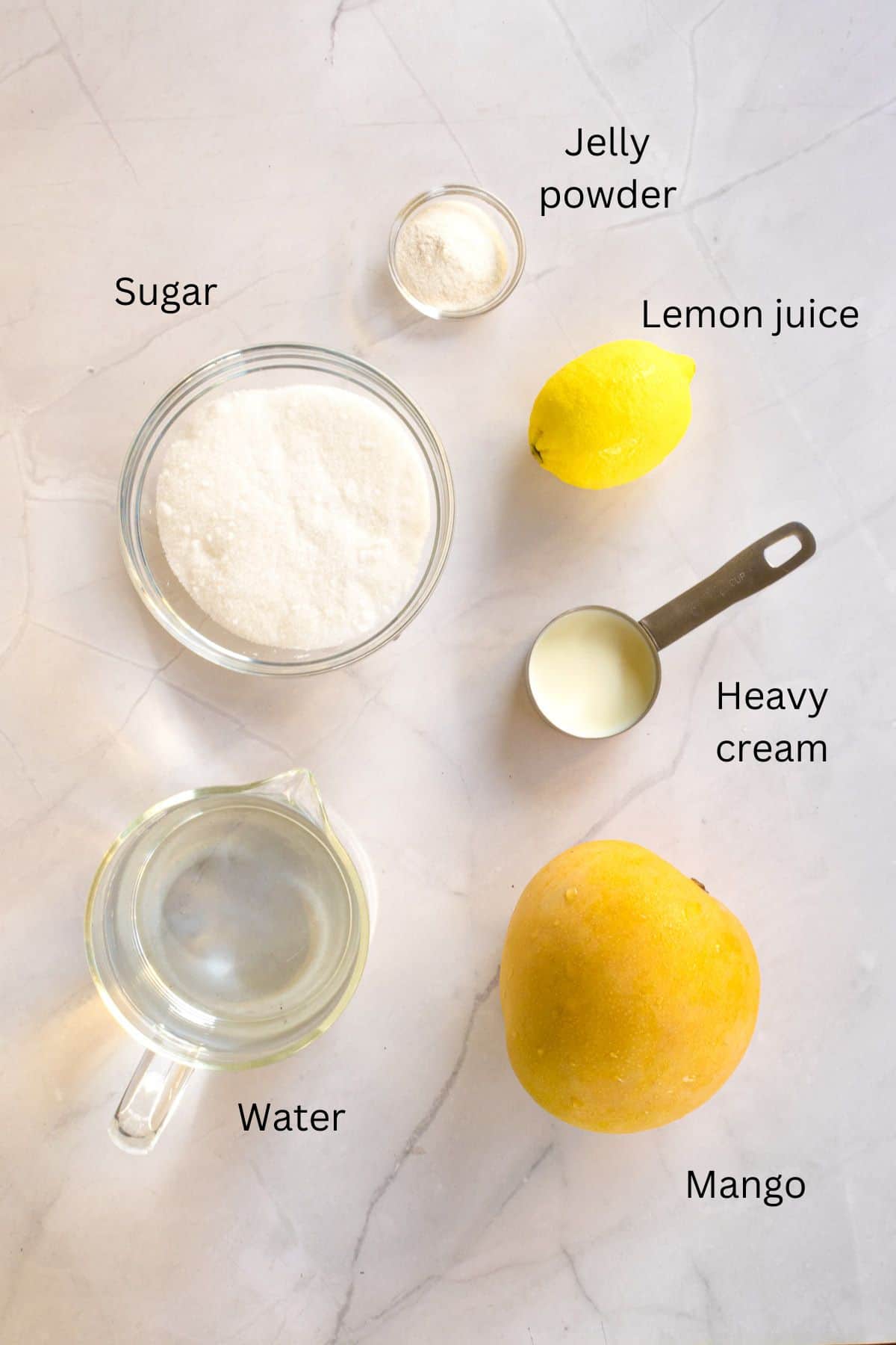 Sugar, agar agar powder, lemon, heavy cream, mango, water against a marble background.