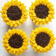 4 cupcakes decorated with yellow buttercream petals and chocolate sprinkles centers to look like flowers.